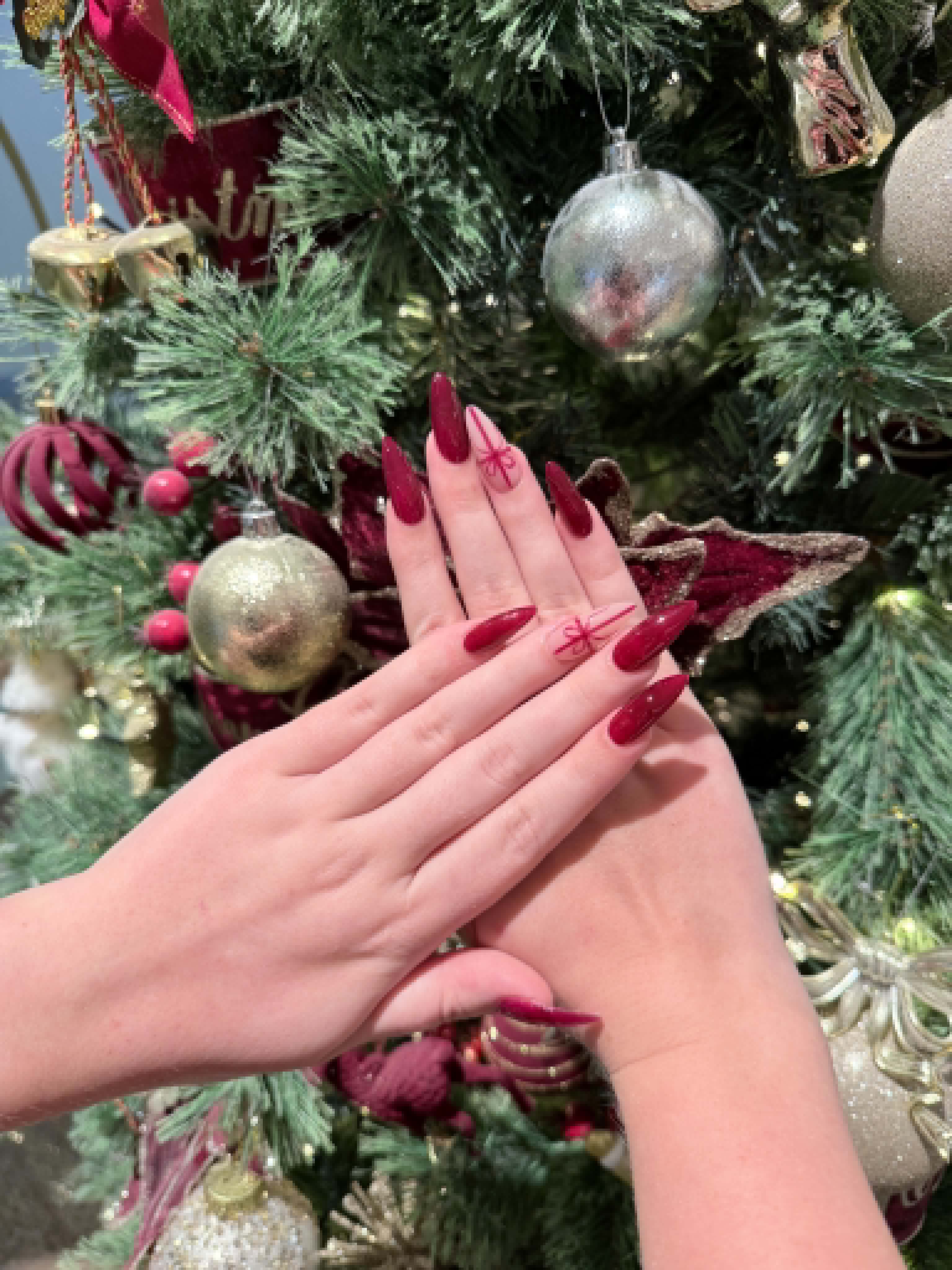 Dark red stiletto nails with Christmas bow art — Caitlyn Nails